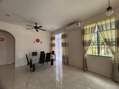 a dining room with a table and a ceiling fan at Big Garden Homestay in Pantai Remis