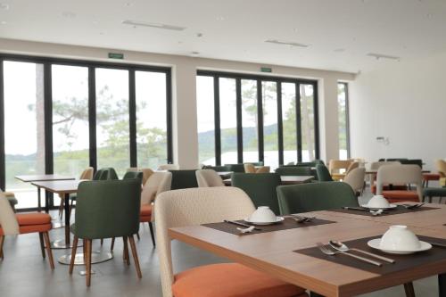 a dining room with tables and chairs and windows at Haven in the Pines in Ðinh An (2)
