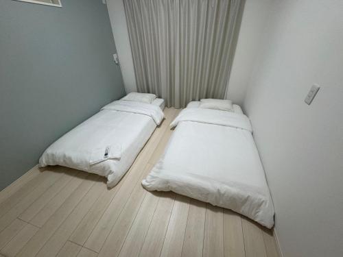 two beds in a room with white walls and wooden floors at 嘉翔の家 in Otsu