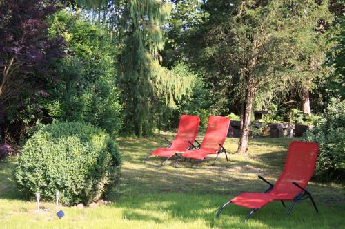 a group of red chairs sitting in the grass at mein kleinHOTEL in Herbstein