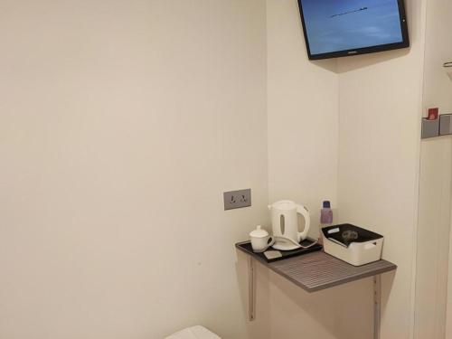 a table with a coffee maker and a tv on a wall at Goodrich Hotel in Hong Kong