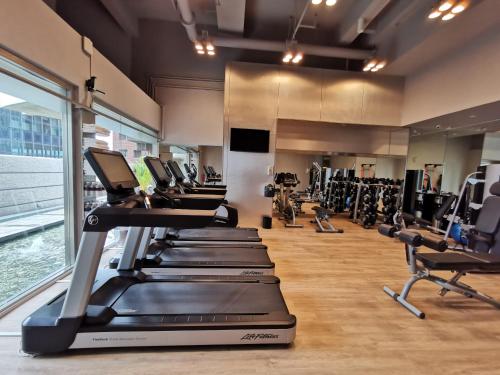 a gym with rows of treadmills and machines at M Hotel Singapore City Centre in Singapore