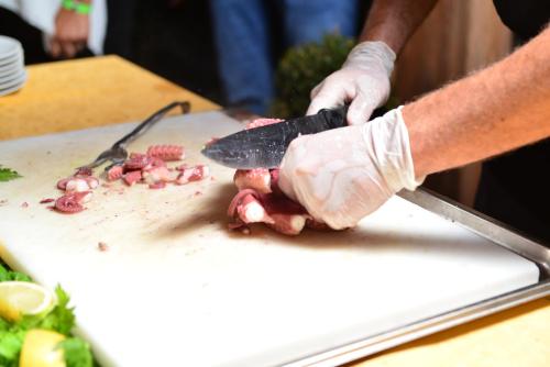 a person in gloves cutting up food on a cutting board at Pantelleria Resort in Pantelleria