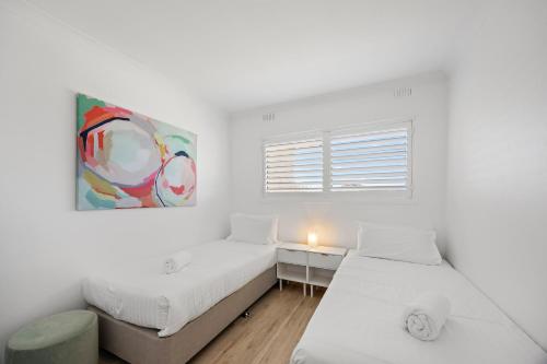 two beds in a white room with a painting on the wall at The Avenue - Fremantle 3 Bed in South Fremantle