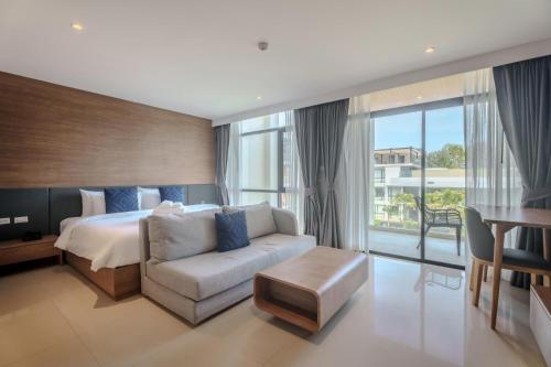 a bedroom with a bed and a couch and a window at Wyndham Gardens 1321 Studio 1m from Naithon Beach in Nai Thon Beach