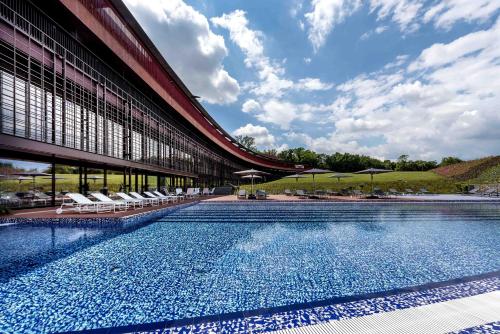 a swimming pool in front of a building with chairs at Villaverde Hotel Spa&Golf Udine in Fagagna