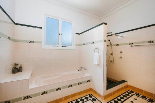 a white bathroom with a tub and a window at Madeira Cottage - Country Comfort with Pool and Spa in Mudgee