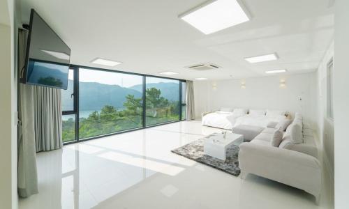 a living room with white furniture and a large window at Yangpyeong River Legend in Yangpyeong