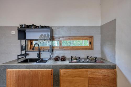 a kitchen with a sink and a stove top oven at Kampuak Cottages in Nusa Penida