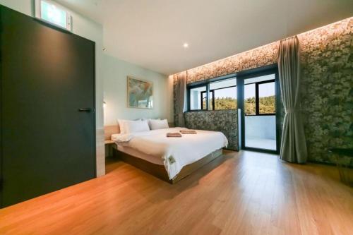a bedroom with a bed and a large window at Changwon Brown dot Hotel Palyong in Changwon