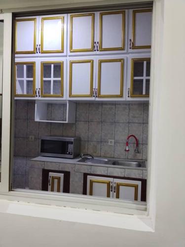 a kitchen with a sink and a microwave at Aloha Suites Odza - by Skyline Residence Services in Yaoundé
