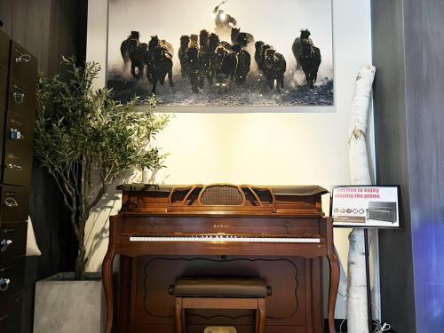 a piano in a room with a picture on the wall at The Centurion Sauna Rest & Stay Sapporo Male Only in Sapporo