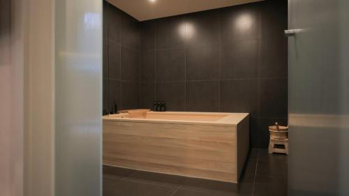 a bathroom with a bath tub with a mirror at Aank Ryokan Hotel Paju in Paju