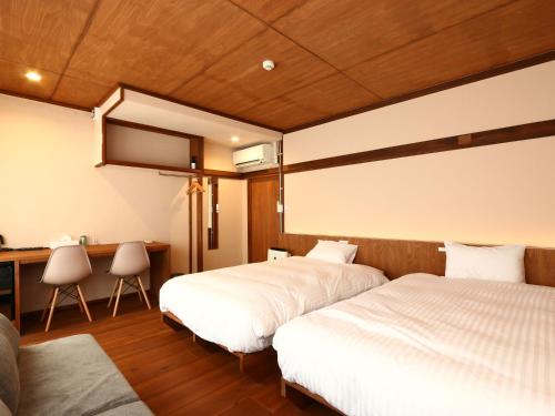 a bedroom with two beds and a desk and a table at nirasakiyaSTAY in Nirasaki