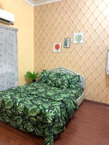 a bedroom with a bed with a green blanket at Purnama Homestay in Kampong Bukit Badong
