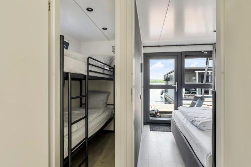 a bedroom with bunk beds and a balcony at Houseboat Mookerplas met Hottub in Middelaar
