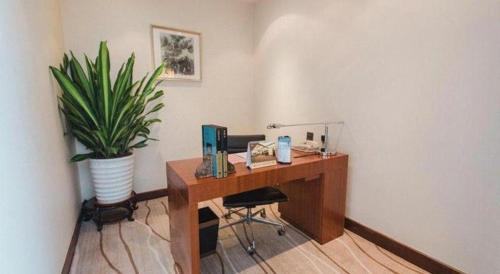 an office with a desk with a potted plant at Grand Soluxe Zhongyou Hotel Shenzhen in Shenzhen