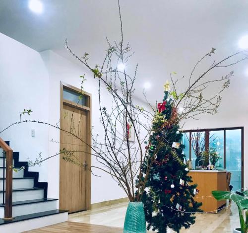 a christmas tree in a vase in a room with stairs at Mie's Homestay in Da Nang