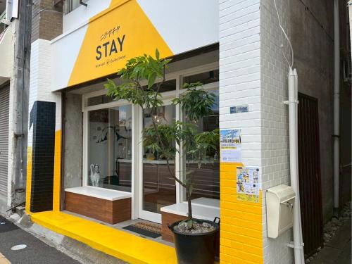 a yellow and white store front with plants in the window at nirasakiyaSTAY in Nirasaki
