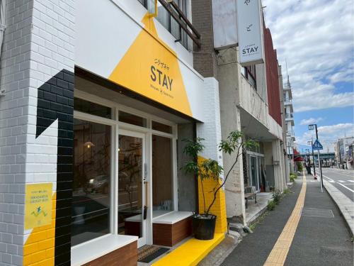 a store with a yellow and black sign on a street at nirasakiyaSTAY in Nirasaki