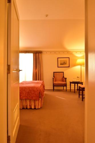 a bedroom with a bed and a chair and a window at Pousada Palacio de Queluz in Queluz