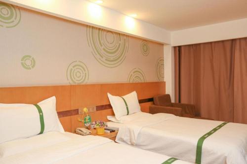 a hotel room with two beds and a chair at GreenTree Inn Jinzhong PinGYAo City South Railway Station Express Hotel in Pingyao