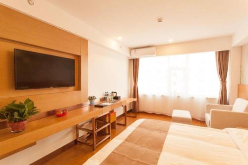 a hotel room with a bed and a desk with a television at GreenTree Inn Jinzhong PinGYAo City South Railway Station Express Hotel in Pingyao