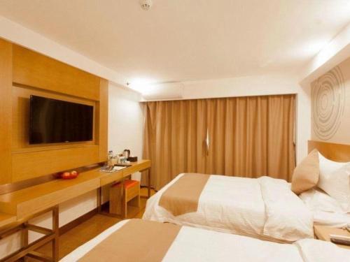 a hotel room with two beds and a desk and a television at GreenTree Inn Jinzhong PinGYAo City South Railway Station Express Hotel in Pingyao