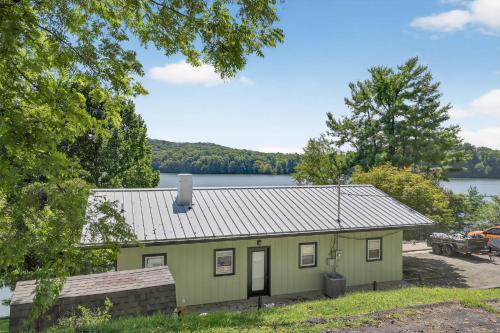 a green house with a lake in the background at Lakefront Getaway with Private Dock & Scenic Views home in Gray