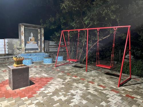 czerwona huśtawka ze statuą w tle w obiekcie Thi Thi Homestay w mieście Yelagiri