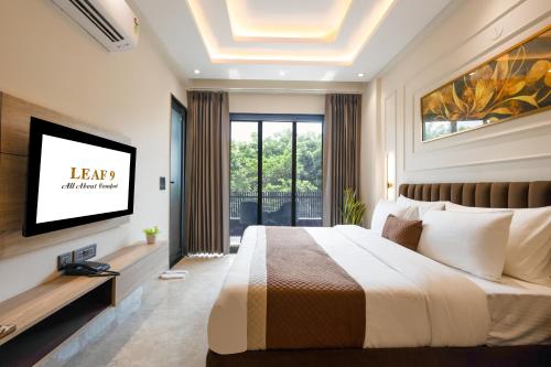 a bedroom with a large bed and a tv at Leaf 9 Grand, Near Udyog vihar and Yashobhoomi in Gurgaon