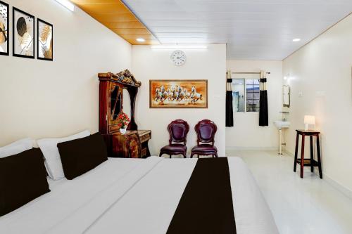 a bedroom with a bed and two chairs at Super Hotel O Chittoor Railway Station Formerly Four Oaks in Chittoor