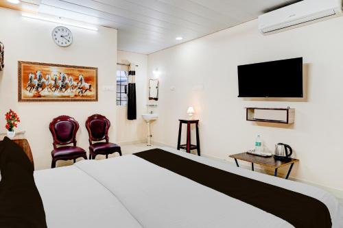 a hotel room with a bed and two chairs at Super Hotel O Chittoor Railway Station Formerly Four Oaks in Chittoor