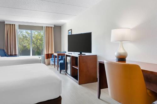 a hotel room with a bed and a desk with a television at Comfort Inn & Suites Orlando North in Sanford