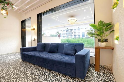 a blue couch in a room with a large window at Super Townhouse Haridwar Vishwakarma Ghat Formerly Haridwar Aagman in Haridwār