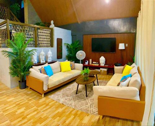 a living room with two couches and a flat screen tv at The Bali Farm in Cabuyao