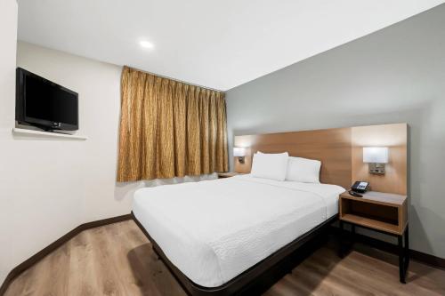 a hotel room with a bed and a flat screen tv at MainStay Suites Raleigh North in Raleigh