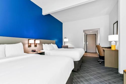 a hotel room with two beds and a desk at Comfort Inn & Suites Grand Blanc-Flint in Grand Blanc