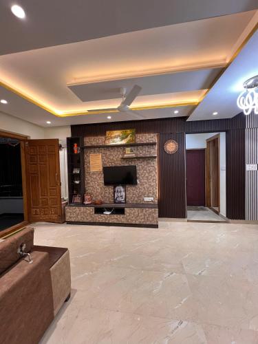 a lobby with a couch and a tv on a wall at #101 Gokula Srigandha Fragrance in Shimoga
