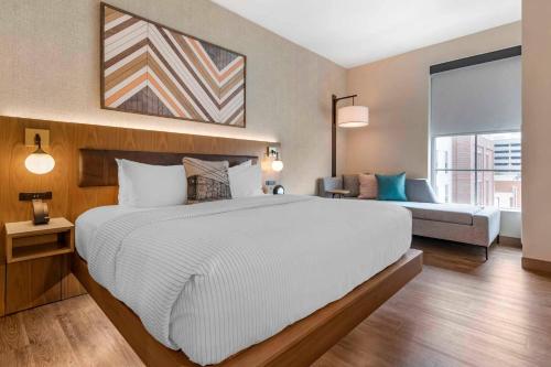 a bedroom with a large white bed and a couch at Cambria Hotel Columbia Downtown the Vista in Columbia