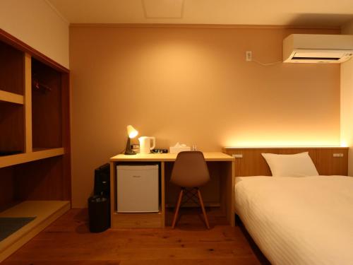 a bedroom with a bed and a desk with a chair at nirasakiyaSTAY in Nirasaki
