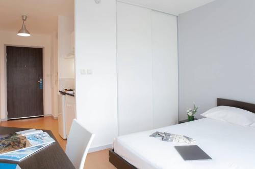 a bedroom with a bed and a desk with a laptop at Comfort Aparthotel Besancon Hauts du Chazal in Besançon