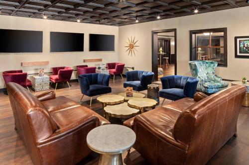 a living room with leather furniture and chairs at The Highlander Hotel, Ascend Hotel Collection in Iowa City