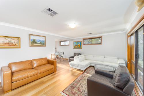 a living room with a couch and a table at Serene Farmhouse with Lake Views in Burrawang