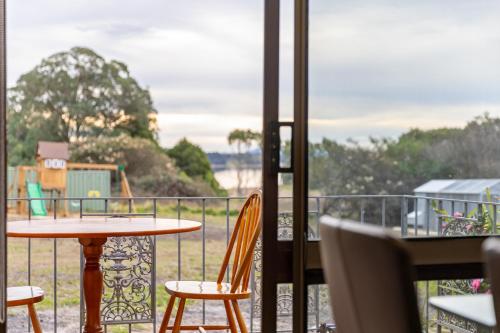 a balcony with a table and chairs and a view of the water at Serene Farmhouse with Lake Views in Burrawang