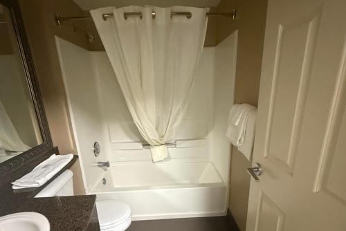 a bathroom with a toilet and a shower with a curtain at Coratel Inn Ocean Shores Extended Stay in Ocean Shores