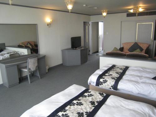 a bedroom with two beds and a desk and a computer at Mamesentaigetsu in Minamichita
