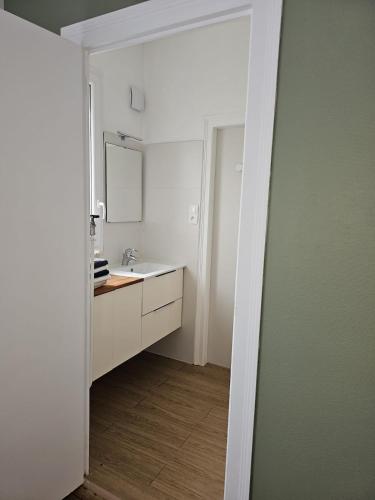 a white bathroom with a sink and a mirror at Maison Aéroport Bourges in Bourges