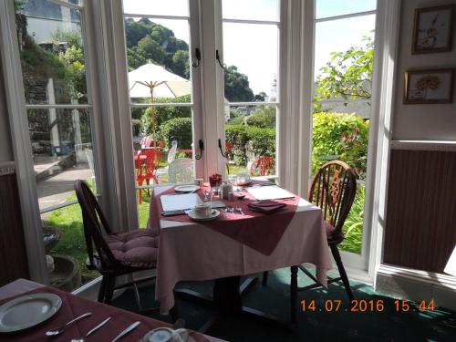 Orchard House Hotel في لينماوث: غرفة طعام مع طاولة وكراسي ونوافذ
