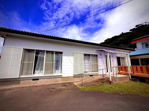 a white house with a fence in front of it at 民泊御座岬 Minpaku Gozamisaki in Goza